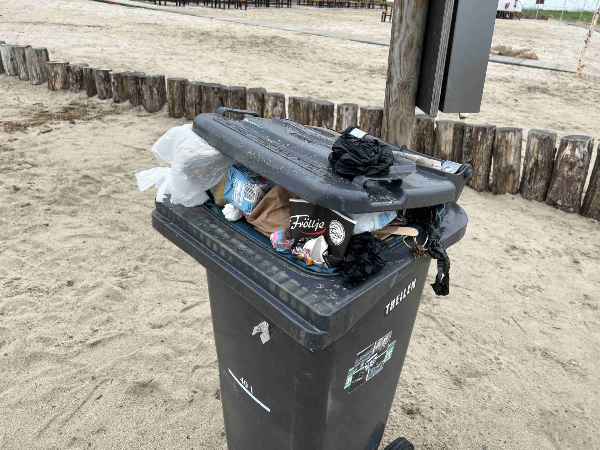 überfüllte Mülltonne am Strand