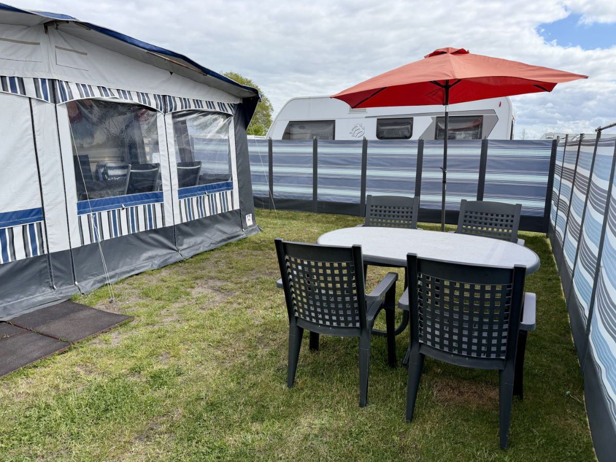 Vorgarten des Mietwohnwagen mit Tisch und vier Stühlen auf dem Strandcampingplatz Dangast
